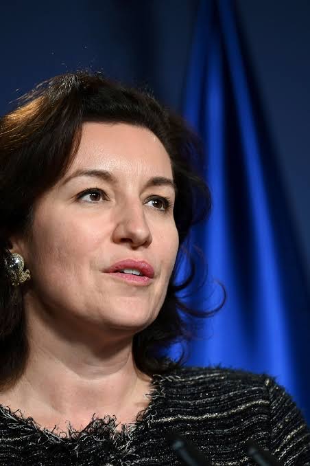 Portrait of Dorothee Bär speaking at a press conference in front of a blue flag